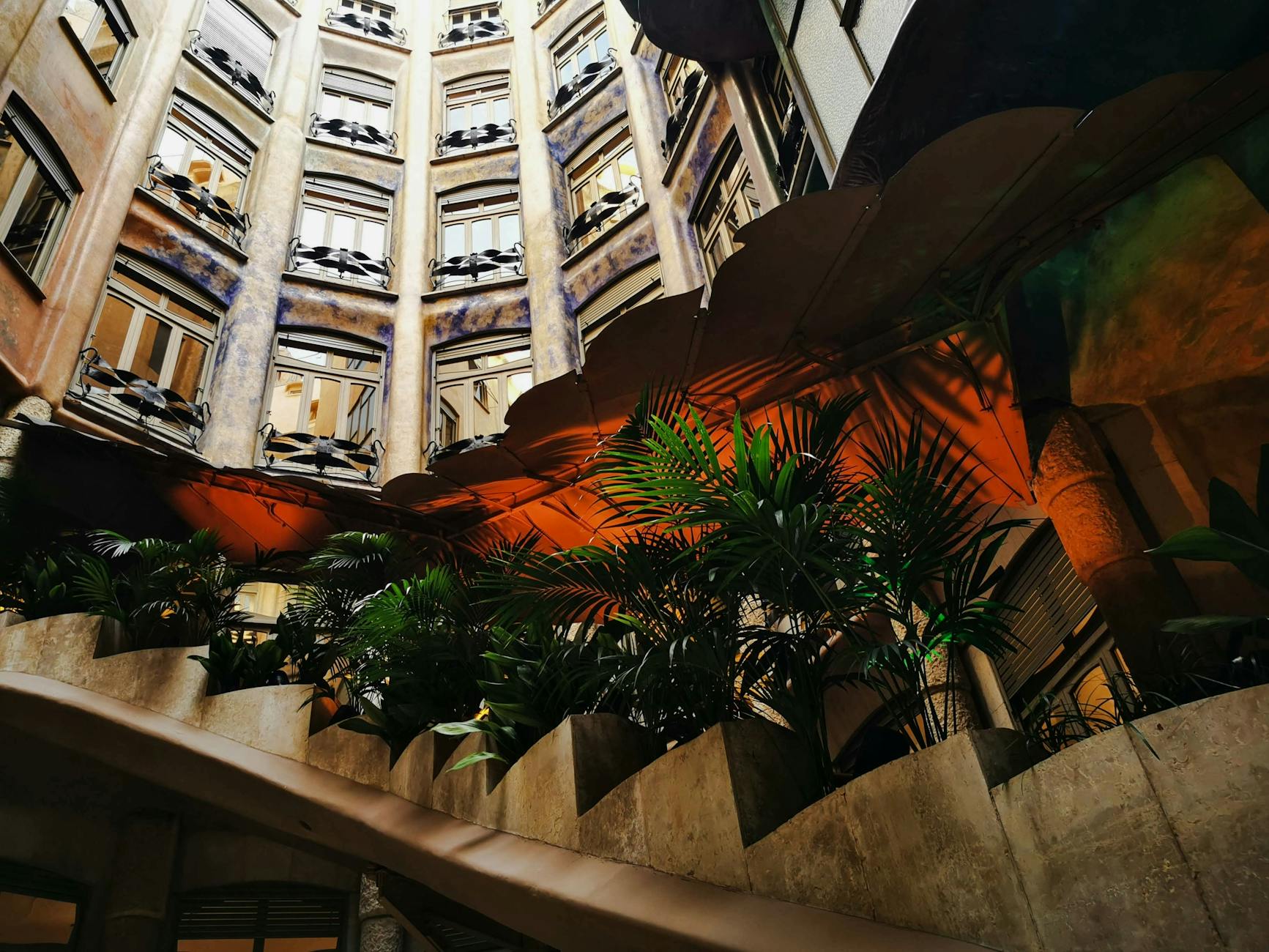 View of Casa Milà's interior courtyard highlighting Gaudí's architectural prowess and lush plants.